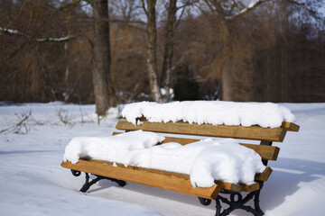 Wooden bench in the snow in a winter park