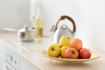 Fruits in plate on table, kettle on stove in modern kitchen, breakfast in morning, healthy food and vitamins