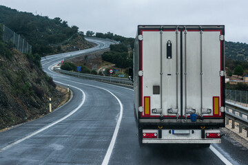 Refrigerated truck driving on a conventional road, with a continuous line and many curves.