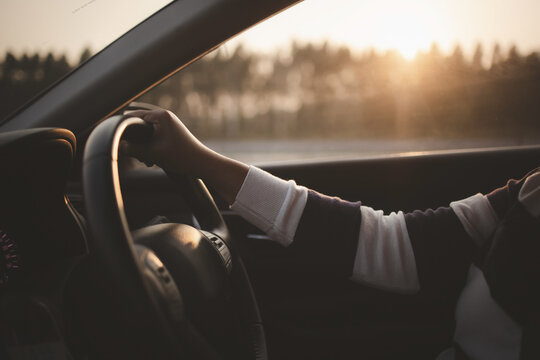 Driving car in sunset or sunrise, Closeup hand on steering wheel driving car in morning or evening
