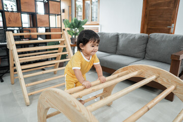 cute baby climbing on pikler triangle toys in the living room