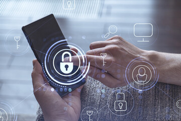 A programmer is browsing the Internet in smart phone to protect a cyber security from hacker attacks and save clients confidential data. Padlock Hologram icons over the typing hands.