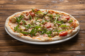 Pizza with bacon, chicken, mushrooms, arugula, tomatoes and mozzarella cheese