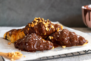 Dark chocolate croissants with nut and flower of salt on top in vintage dark stone background. Tasty and freshly croissants. 