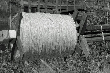 Black-white: Close-up of a huge medieval spool or spindle with white wool yarn
