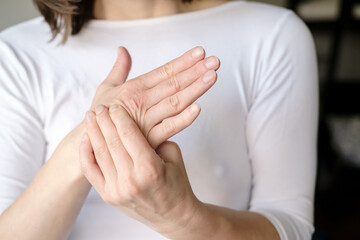 The woman experiences pain in her arm and massages her sore palm. 