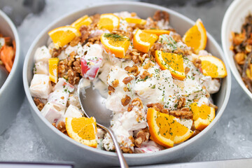 Potato salad and fresh orange with walnut on salad bar. 