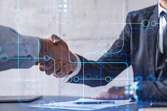 Handshake of two businessmen who enters into the contract to develop a new software to improve business service at a company. Technological icons over the table with the document.