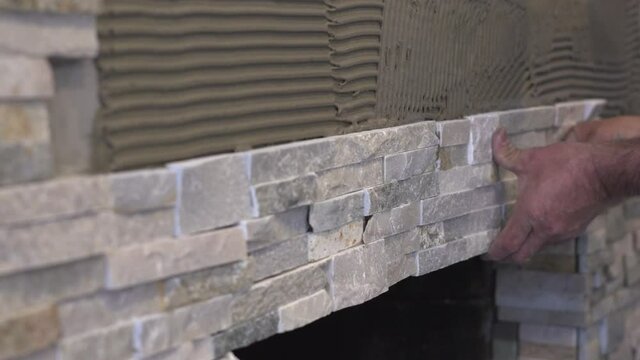Male Worker Hands Setting Stacked Stone Tiles for a Fireplace