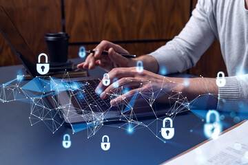 A programmer is typing a code on a keyboard to protect a cyber security from hacker attacks and save clients confidential data. Padlock Hologram icons over the typing hands.