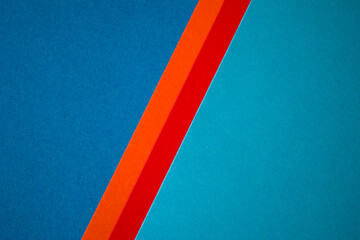 Two tone blue colored paper divided with red and orange stripes background