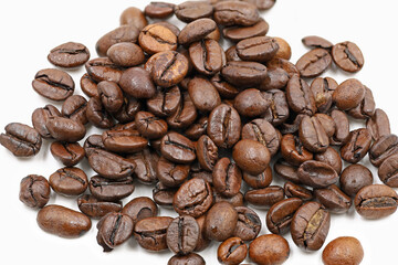 Roasted coffee beans heap isolated on white background, close up