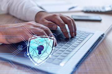 A programmer is typing a code on computer to protect a cyber security from hacker attacks and save clients confidential data. Padlock Hologram icons over the typing hands. Formal wear.