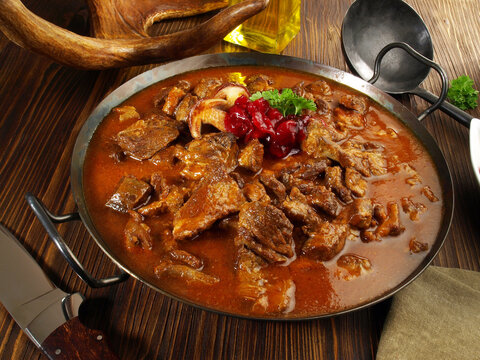 Wild Game Meat Goulash In A Pan With Cranberries On Wooden Background