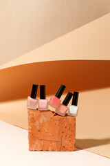 Set of nail polish bottles neutral natural colors on brick podium on beige background. Concept of pallete for french manicure, beauty cosmetology, handcare, beautician industry, banner, copy space - 415610330