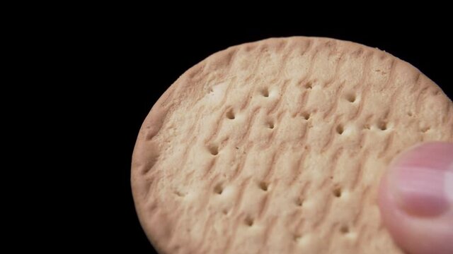 Round crispy cookies in hand on a black background. Macro shot. Baked golden texture