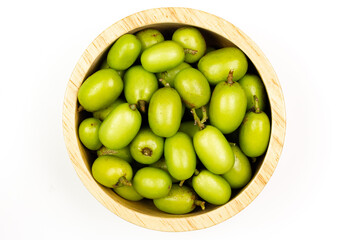Fresh Neem fruit on wooden bowl isolated on white background, Top view. Neem fruit is an excellent moisturizing and contains various compounds that have insecticidal and medicinal properties.