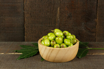 Fresh Neem fruit in wooden bowl with leaf on wooden background. Neem fruit is an excellent moisturizing and contains various compounds that have insecticidal and medicinal properties.