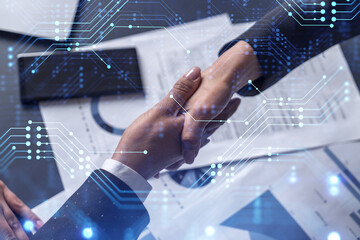 Handshake of two businesswomen who enters into the contract to develop a new software to improve business service at a company. Technological icons over the table with the document.