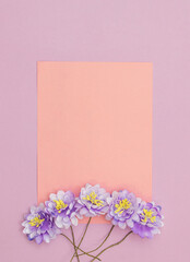 Orange paper note and five blue blooms on violet background.