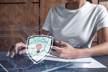 A woman programmer is typing a code on computer to protect a cyber security from hacker attacks and save clients confidential data. Padlock Hologram icons over the typing hands. Casual wear.