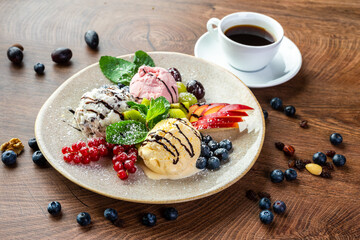 
Ice cream dessert. Three multi-colored balls of ice cream, decorated with fruits, berries and mint, on a large plate 