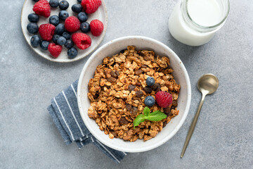 Granola bowl with raisins, nuts and fresh berries. Homemade crunchy granola on grey concrete background, top view