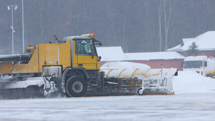 Snowy winter - a big snowplow removes snow from the path on the way