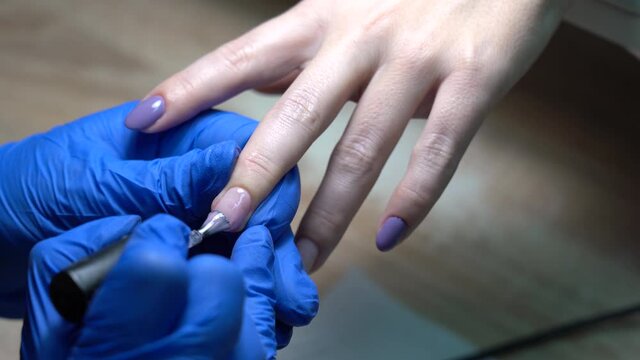 Closeup view 4k stock video footage of professional manicurist painting nails of client with pink pastel gel polish lacquer in beauty spa salon