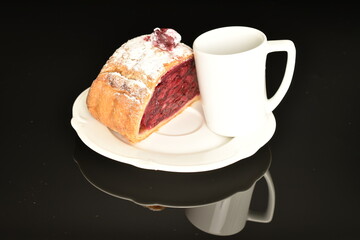 Hot cherry roll with a white coffee cup on a white ceramic saucer, on a white background.