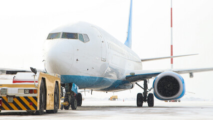 A big blue and white airplane standing on the airfield attached to the transporter