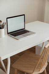 Laptop computer with blank screen on table. Aesthetic minimal office workspace interior design template with mockup copy space.
