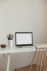 Laptop computer with blank screen on table. Aesthetic minimal office workspace interior design...