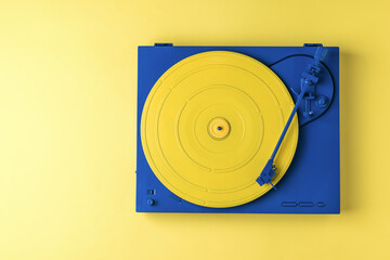 Retro vinyl record player in a stylish color scheme on a yellow background.