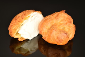 One fragrant cut in half Chouquettes, close-up, on a black background.