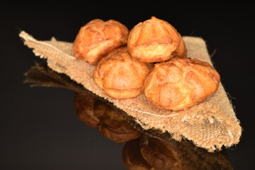 Several sweet shukets on a jute napkin, close-up, on a black background.