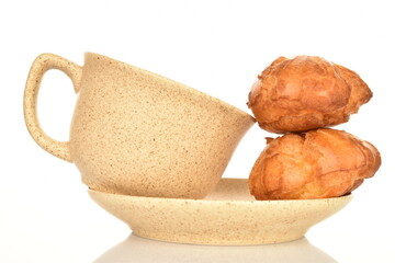 Two fragrant chouquettes on a ceramic saucer with a cup, on a white background.