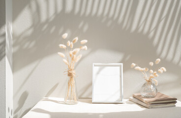 Blank mockup picture frame ,craft diary and dried flower in glass vase on beige table and cement wall background