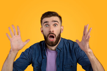 Portrait of shocked man with open mouth looking at camera in amazement, making surprised gesture over orange background