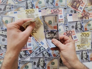 Background dollar and euro.Hand holding money.  Hand holding one hundred dollars and two hundred euros.