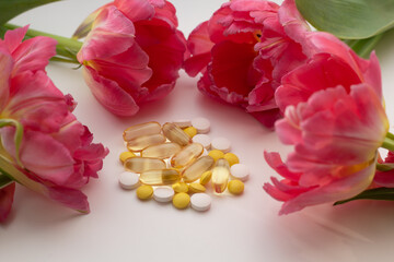Obraz premium Concept of supplementation for spring. Closeup of vitamin D, zinc and vitamin C pills surrounded by flowers.