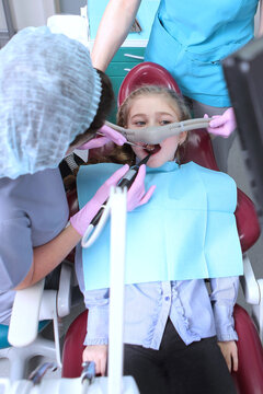 Treatment Of Milk Teeth With Nitrous Oxide. Little Girl Watches TV During Dental Treatment. Comfort And Peace Of Mind When Treating Milk Teeth. Photos In The Interior Of The Clinic. .