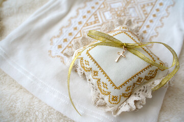 Gold cross on the pillow and shirt for the baptism of a newborn boy. Accessories for christening a child                                