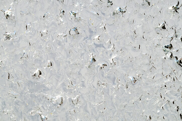 Transparent Ice Floe with cracked crystals with bubbles texture background against light. Cold winter ice texture. close up, macro abstract pattern detail
