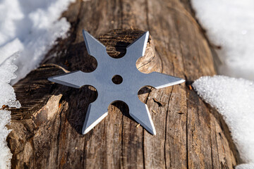 Shuriken (throwing star), traditional japanese ninja cold weapon stuck in wooden background © Sergii