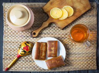 Filled pancakes and tea with lemon for the Maslenitsa holiday in Russian rustic style, flat lay