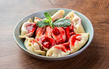 Dumplings with cherries, decorated with mint leaves. Ukrainian cuisine dishes.