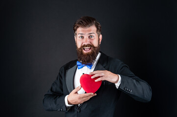 Love symbol. love and romance. brutal bearded guy hold romantic heart. 14 february.