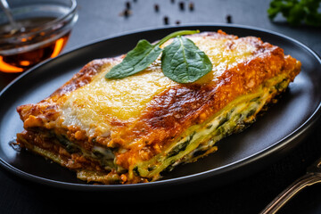 Lasagna with pork and spinach on black table
