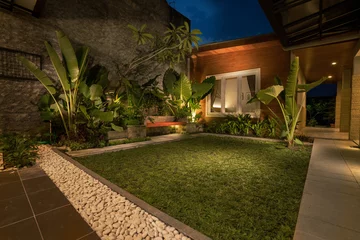 Fotobehang Chocoladebruin tropical Backyard Garden Illumination. Illuminated Garden at Night with Various of Plants  © Odua Images